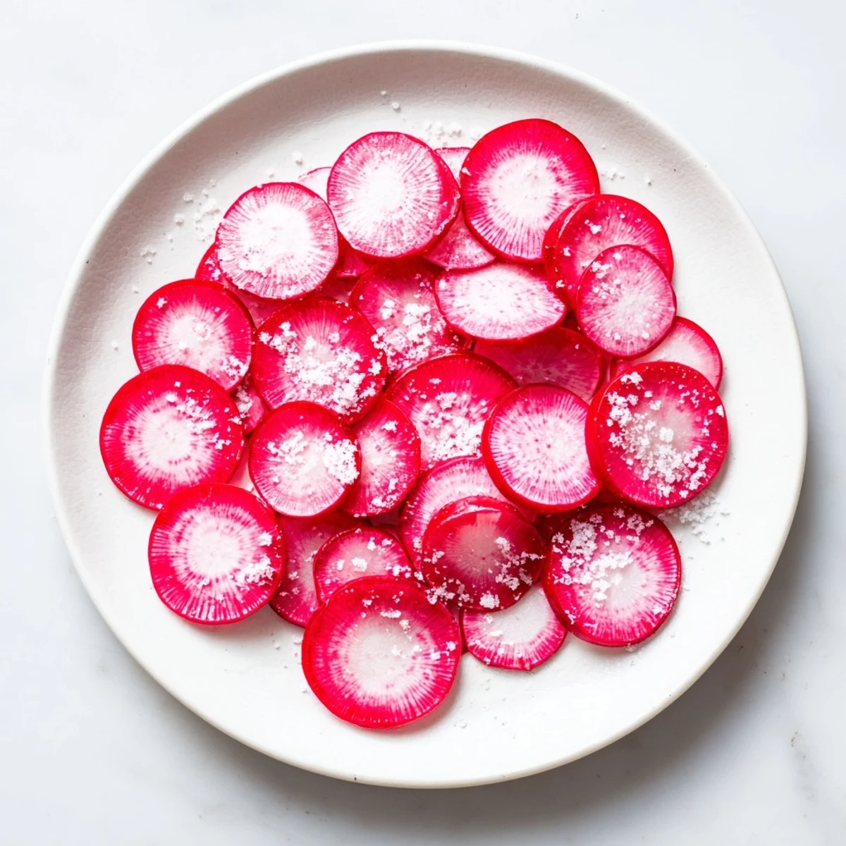 Freshly sliced radish slices with sea salt, a vibrant, crunchy appetizer, ready to enjoy at the table.