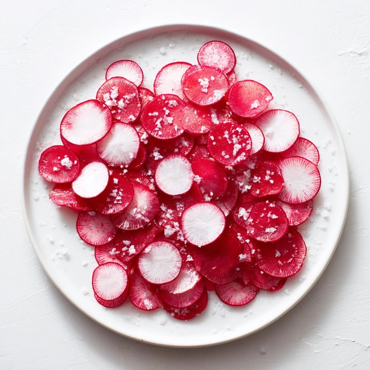 Thin, pink radish slices sprinkled with sea salt appear refreshing, perfect for a quick, healthy snack.