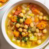 Close-up of Quick-Soak Chickpea and Rosemary Soup; broth simmered with tender chickpeas and rosemary sprigs.