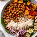 This delicious Roasted Chickpea Buddha Bowl features fluffy rice and creamy tahini sauce drizzled over fresh greens.