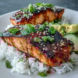 A vibrant Honey Sriracha Salmon Bowl garnished with green onions and sesame seeds, drizzled with spicy mayo.  