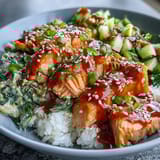 A vibrant bang bang salmon bowl topped with crisp cucumbers, edamame, and toasted sesame seeds for added crunch.