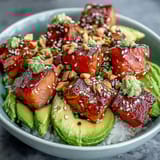 Close-up of an Avocado Salmon Bowl featuring marinated salmon cubes, creamy avocado slices, and crisp cucumber over seasoned sushi rice.