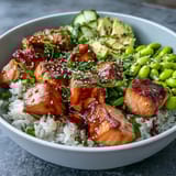 This Salmon Rice Bowl is finished with spicy sriracha mayo, edamame, and toasted sesame seeds for added flavor.