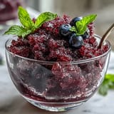 Shaved Black Currant Granita served in a chilled glass with fresh mint and a spoon.