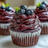 Swirled Black Currant Frosting on a slice of layer cake, showcasing its silky texture and berry hue.