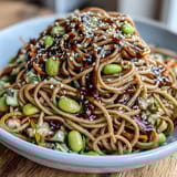 Refreshing sesame ginger noodle bowl featuring cold soba noodles, shredded veggies, and protein-rich edamame tossed in zesty sesame dressing.