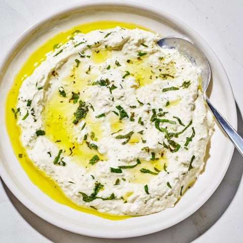 Creamy whipped feta dip with vibrant lemon-mint drizzle, ideal for serving with fresh vegetables.