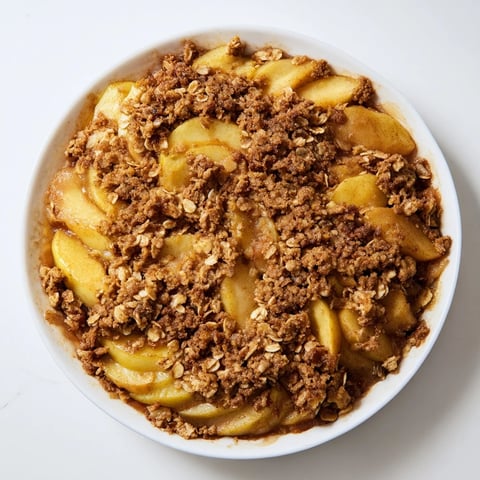 Steaming, warm cinnamon oat apple crisp, perfect for a comforting dessert on a cold day.