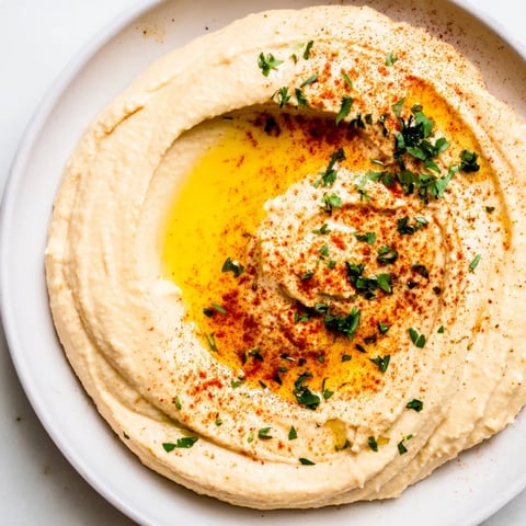 Creamy Levantine hummus plate drizzled with olive oil, ready to be scooped up with warm pita.