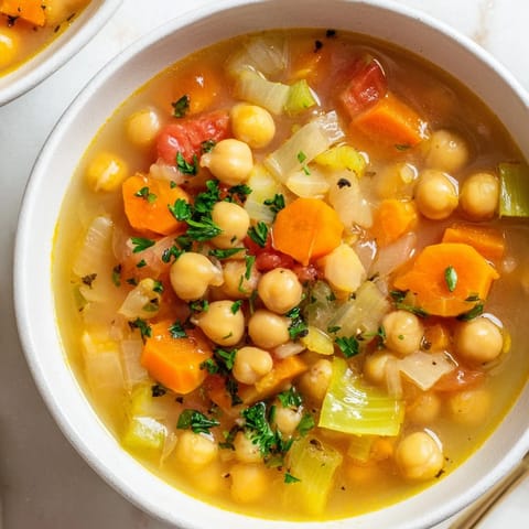Close-up of Quick-Soak Chickpea and Rosemary Soup; broth simmered with tender chickpeas and rosemary sprigs.