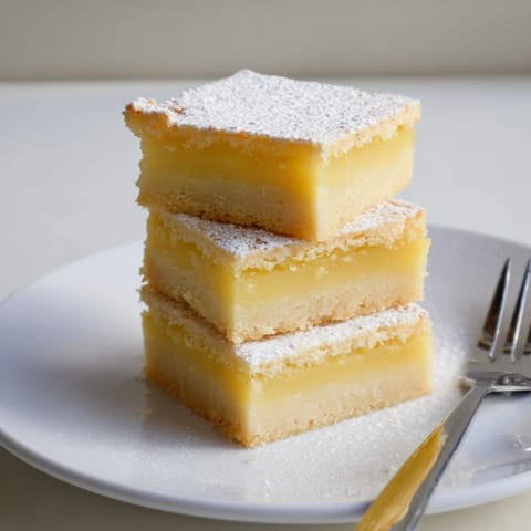 A close-up of buttery lemon bars cut into neat triangles, perfect for a spring dessert.