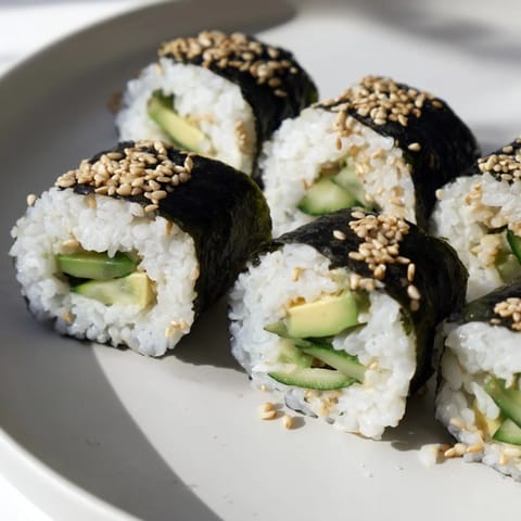 Sliced avocado and cucumber reveal the fresh fillings of these delicious avocado cucumber sushi rolls ready to serve.