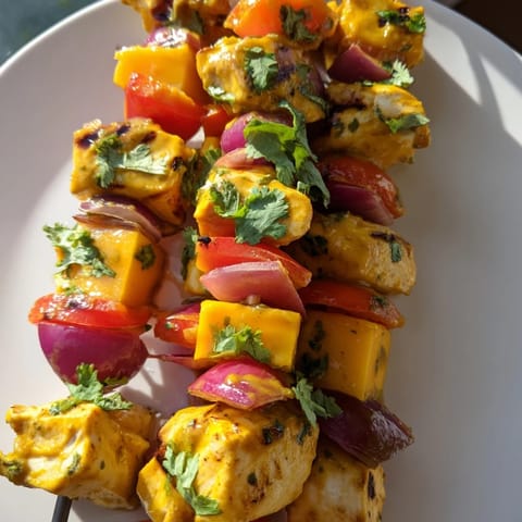 Brightly colored Mango Lime Chicken Skewers with charred chicken and fresh mango chunks ready to eat.