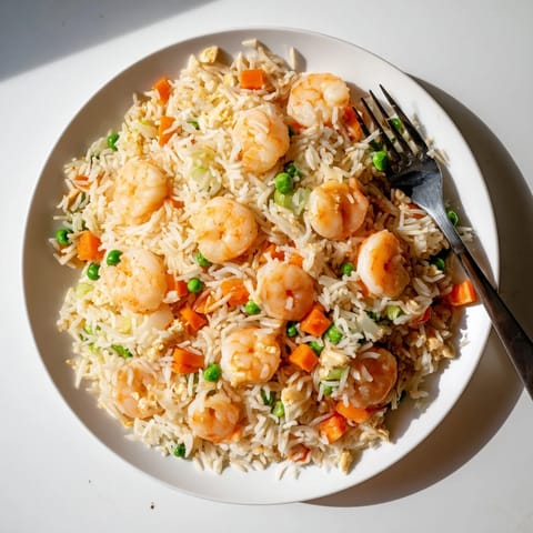 A wok of Shrimp Garlic Fried Rice features tender seafood, crisp carrots, and aromatic soy sauce for a quick weeknight dinner.  