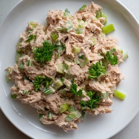 A close-up view of Spicy Zesty Tuna Salad, highlighting flaky tuna mixed with vibrant green scallions and a zesty lemon drizzle.