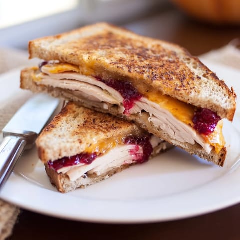 This warm Smoked Turkey Grilled Cheese is sliced to show the gooey, savory interior on a rustic wooden board.
