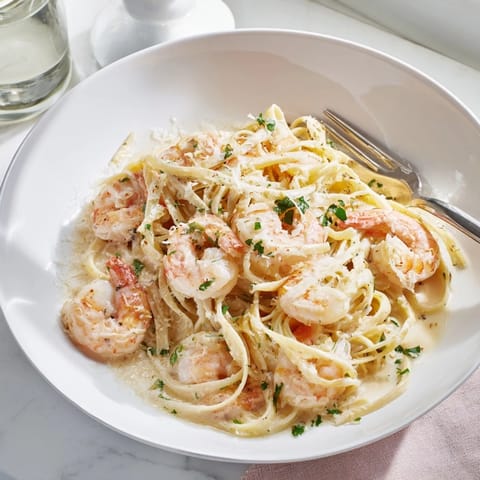 Creamy Garlic Shrimp Pasta in a white bowl, showcasing succulent shrimp and linguine coated in a luscious garlic cream sauce, garnished with fresh parsley.
