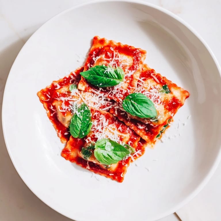 Freshly plated Spinach Ricotta Ravioli with tender pasta, wilted spinach, and ricotta filling, drizzled with savory Italian marinara sauce.