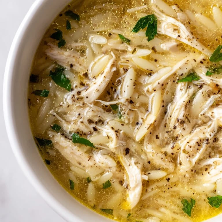 Cozy Comfort: Lemon Pepper Chicken Orzo Soup in a rustic bowl, garnished with parsley and lemon, perfect for chilly March nights.