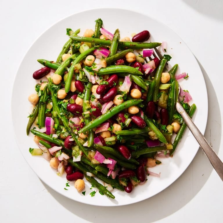 A fresh Three-Bean Salad served in a rustic bowl, garnished with crisp celery and red onion, perfect for a summer picnic or potluck.