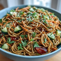 Cold soba noodle salad with sesame ginger dressing, vibrant with fresh crisp vegetables.